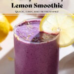 Bright purple smoothie in a short glass garnished with a slice of lemon and fresh lemon zest.