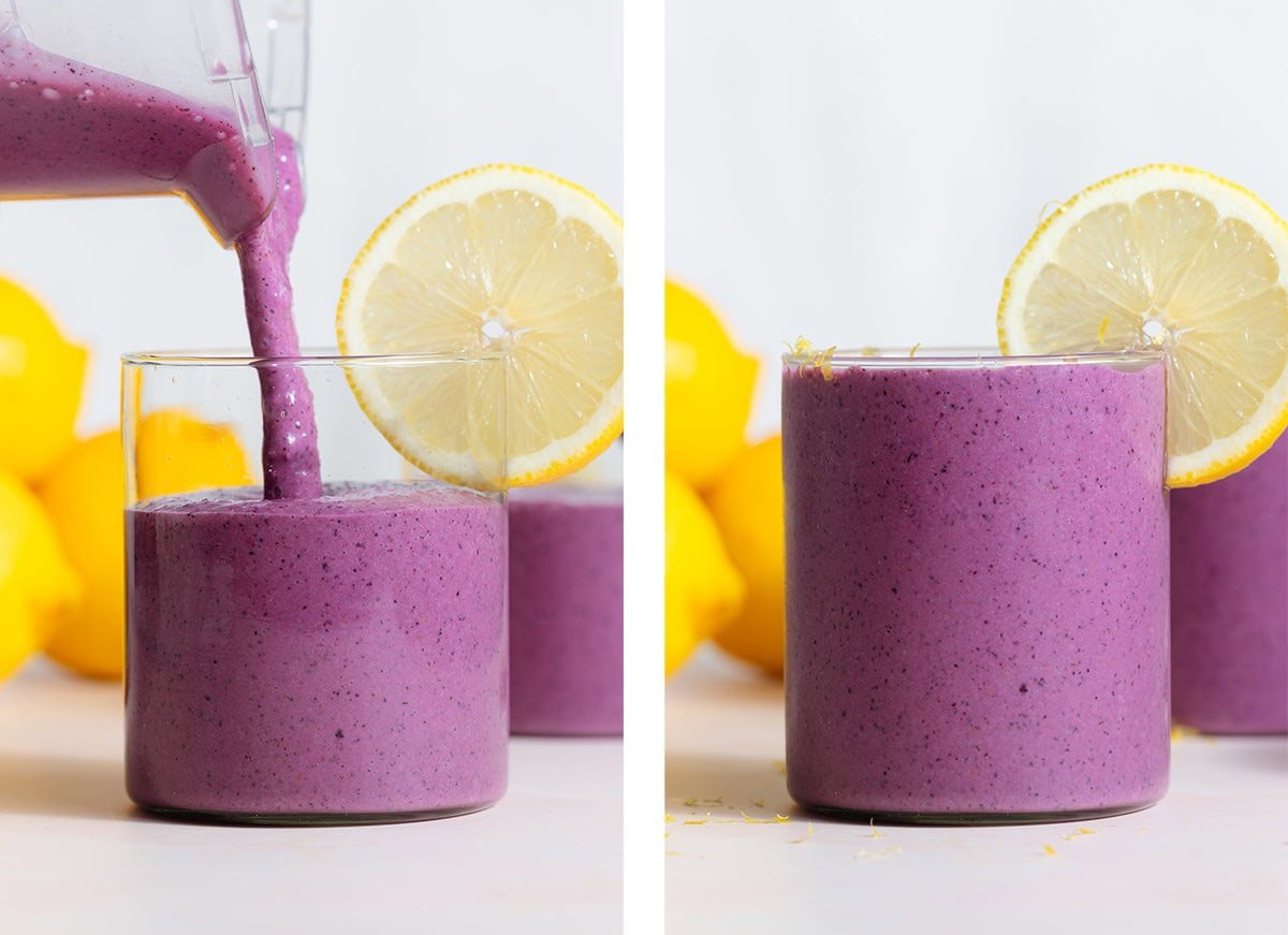 Purple smoothie being poured into a small glass with a slice of lemon on the rim as garnish.