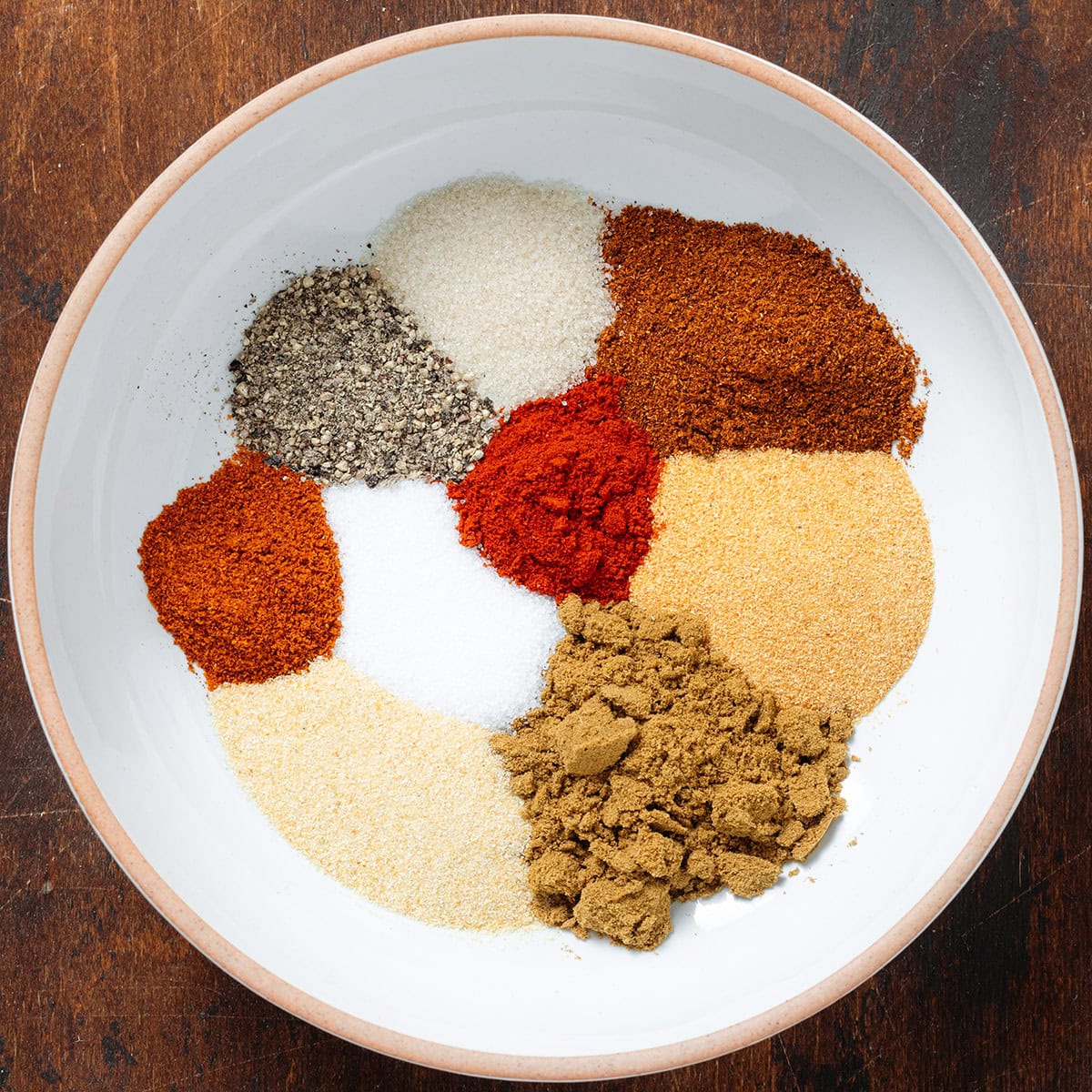 Spices like cumin, garlic powder, chili powder, and paprika in a low white bowl.