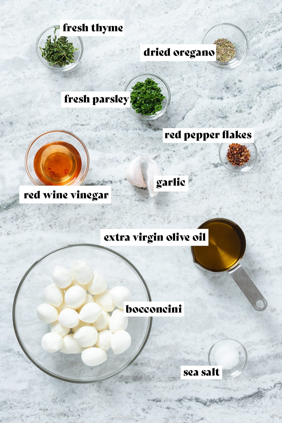 Mini mozzarella balls, olive oil, vinegar, fresh herbs, and garlic in small bowls.