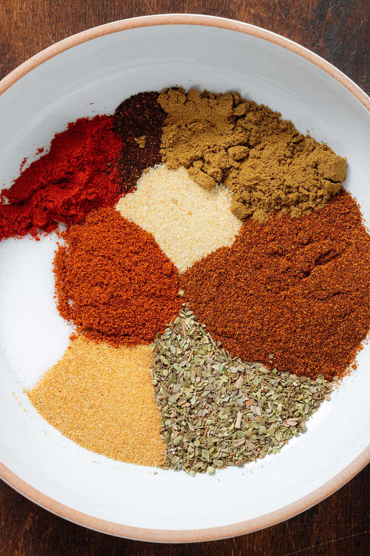 Taco spices, dried oregano, and sea salt in a low white bowl with an orange rim.