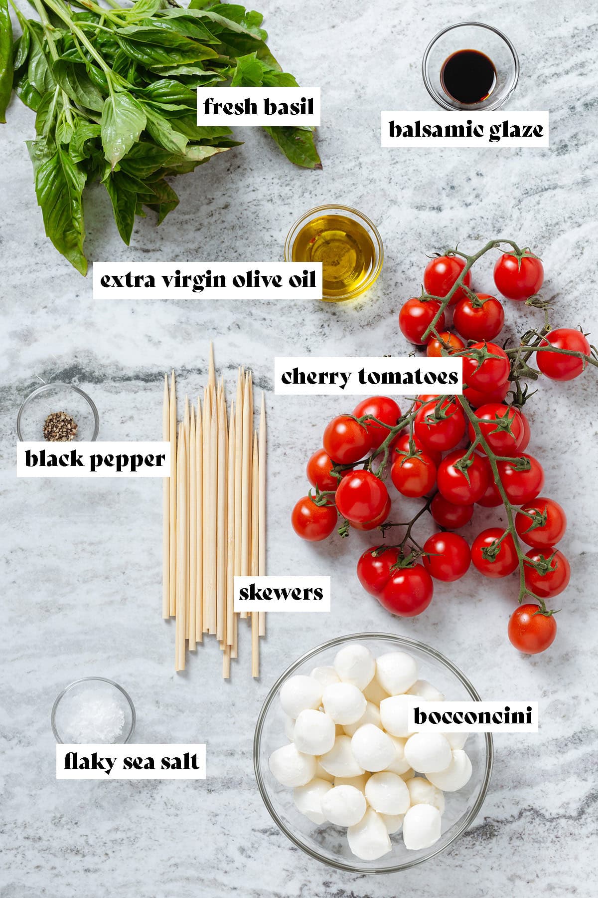 Fresh basil, cherry tomatoes, bocconcini, bamboo skewers, olive oil, and balsamic glaze in small glass bowls with text overlay.