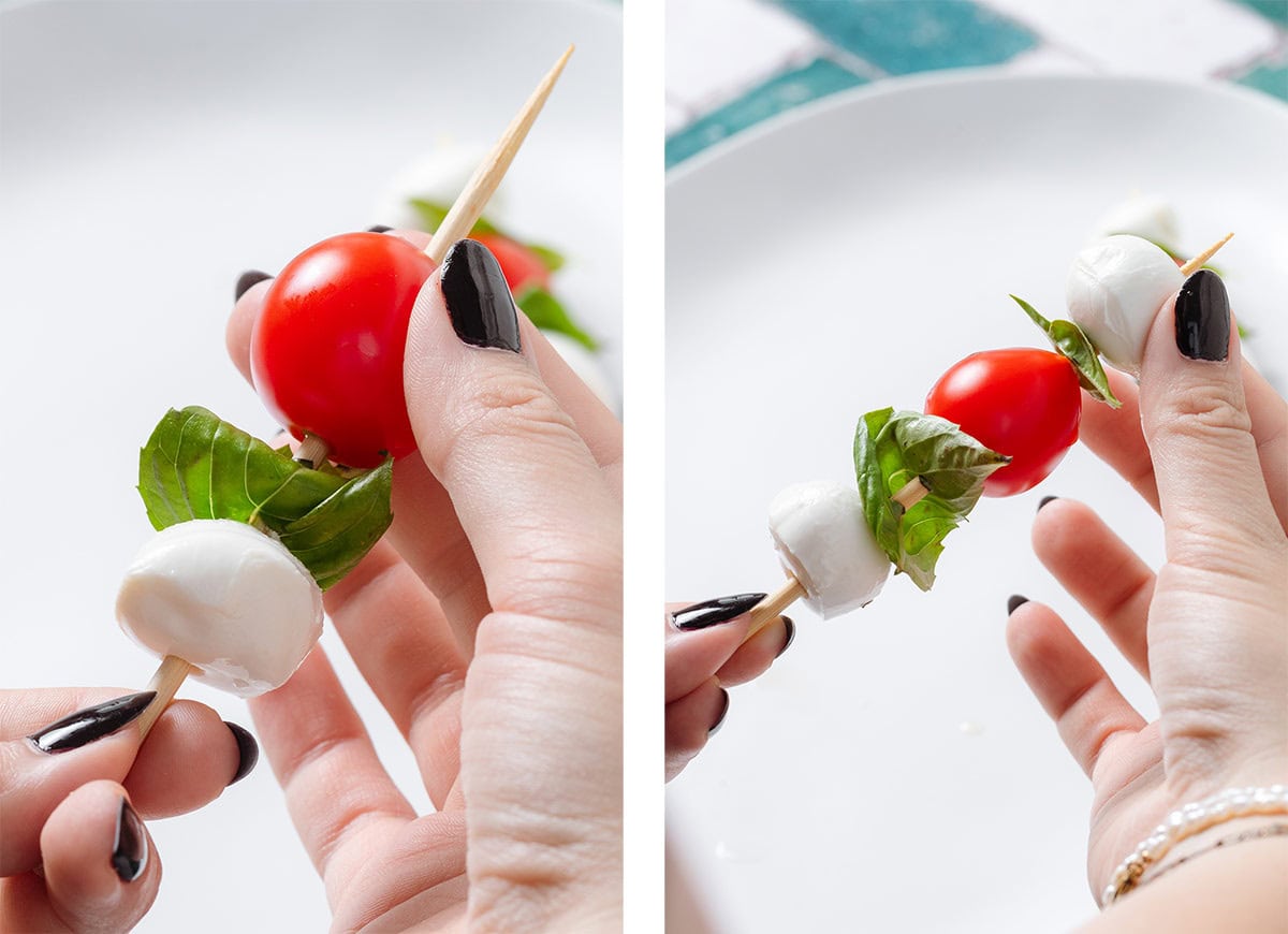 A hand placing cherry tomatoes, mini mozzarella, and fresh basil on a bamboo skewer.