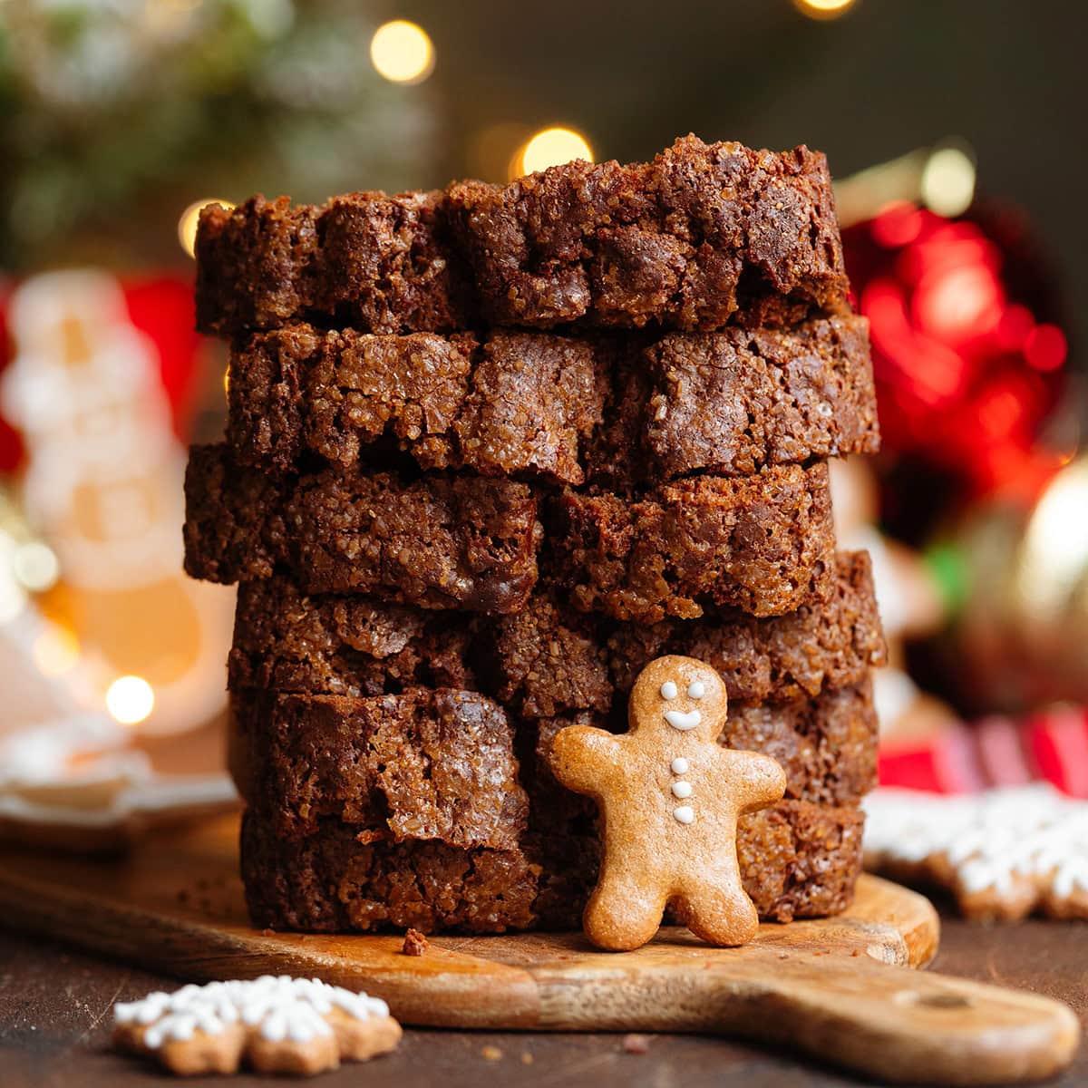 Dark brown gingerbread banana bread slices stacked on top of each other with a small gingerbread man leaning on them in the front.