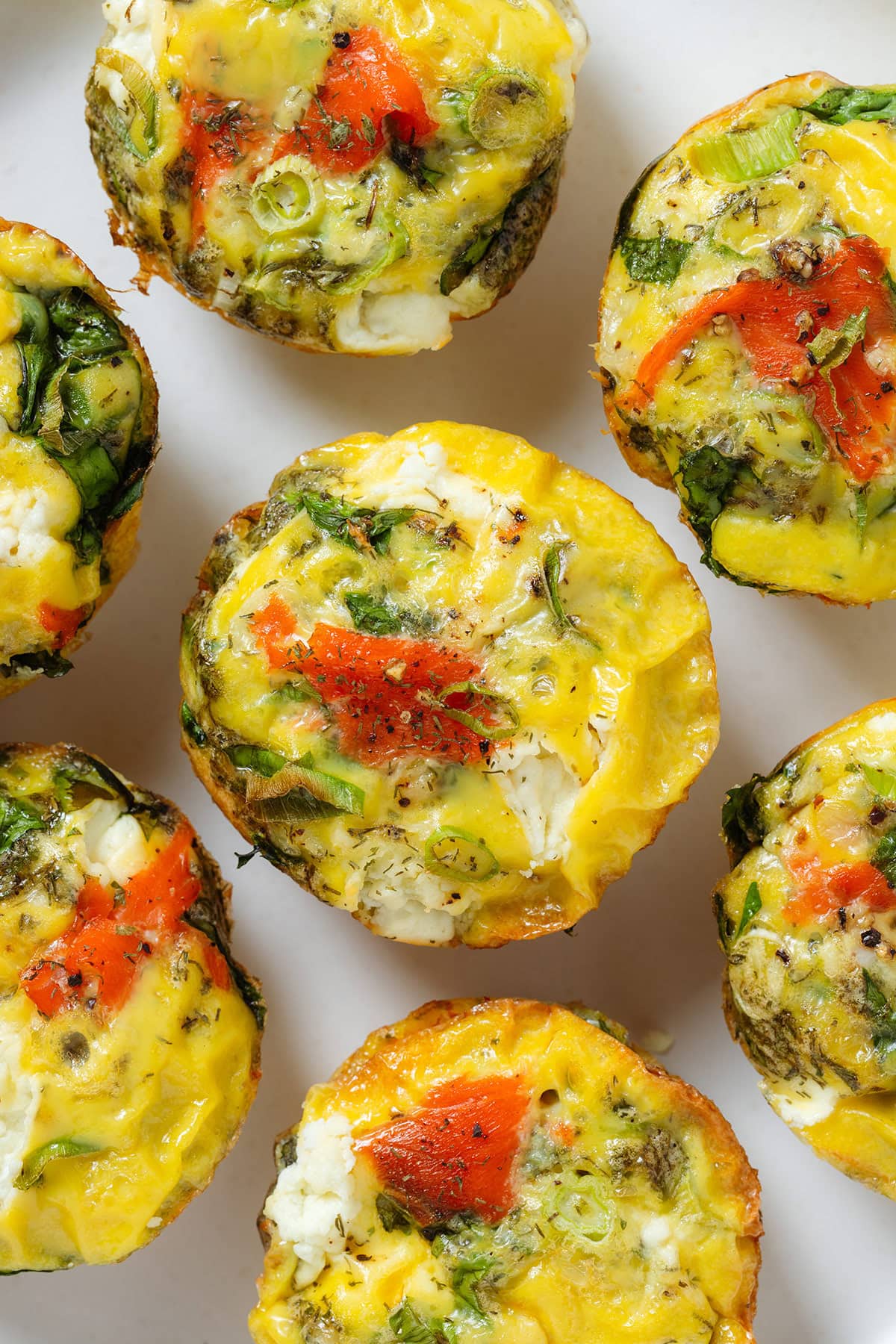 Egg muffins with smoked salmon, cream cheese, and spinach on a white plate.