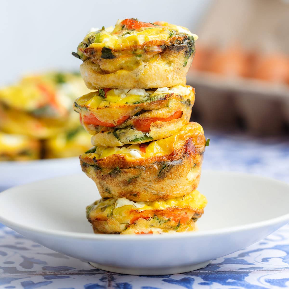 Four smoked salmon egg muffins stacked on a small white plate.