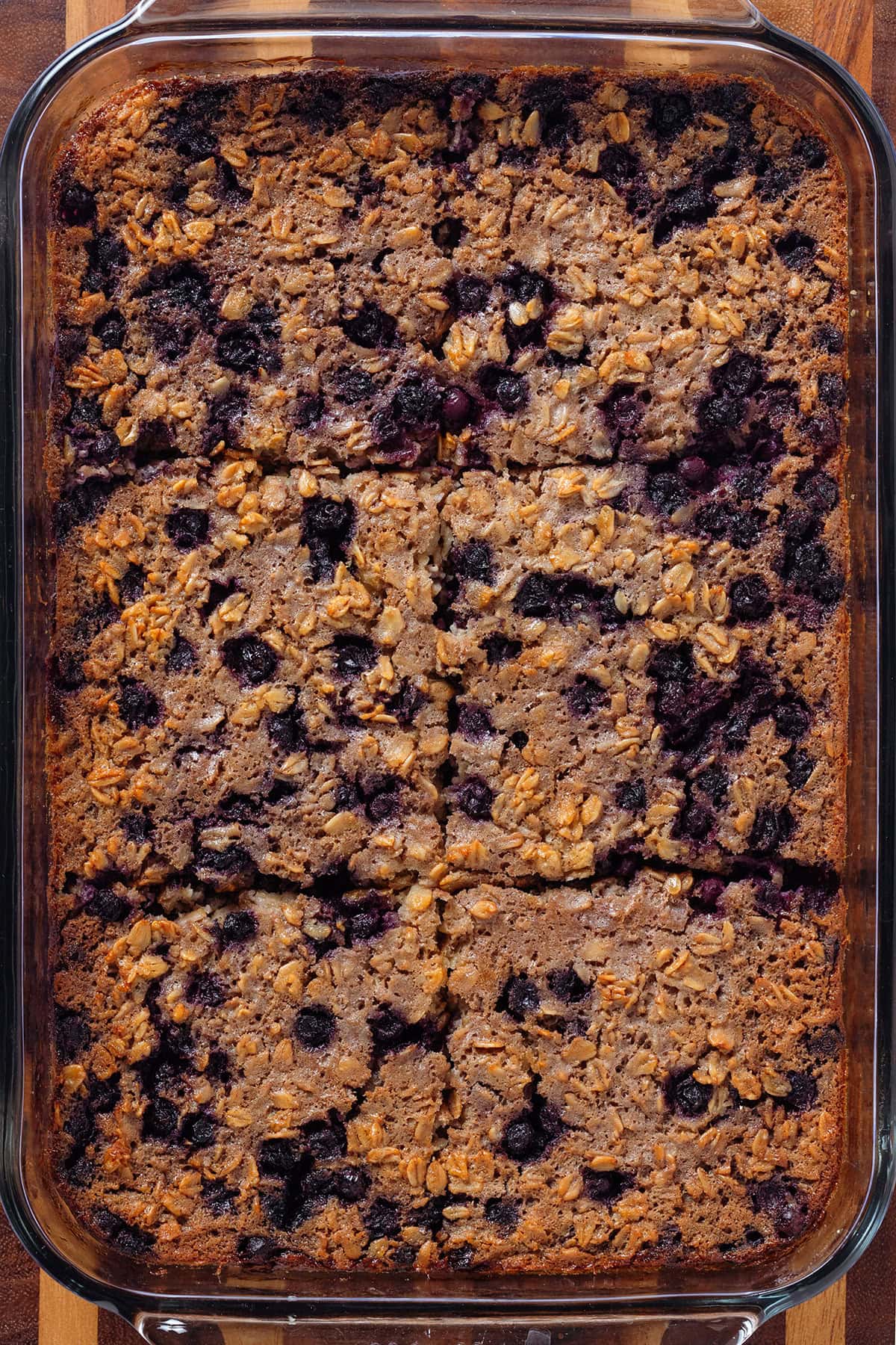 Baked oatmeal with blueberries cut into 6 squares in a glass baking dish.