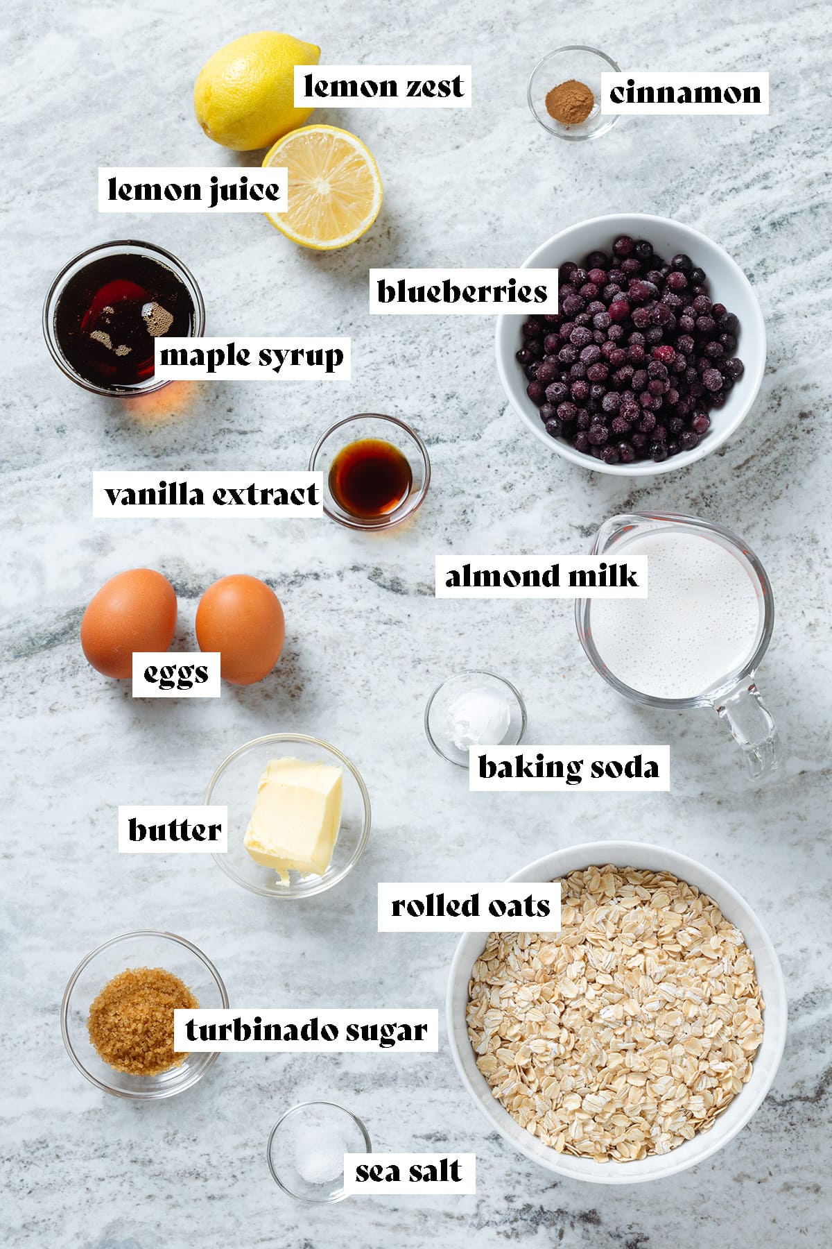 Ingredients like rolled oats, blueberries, almond milk, maple syrup, and other ingredients measured in small bowls.