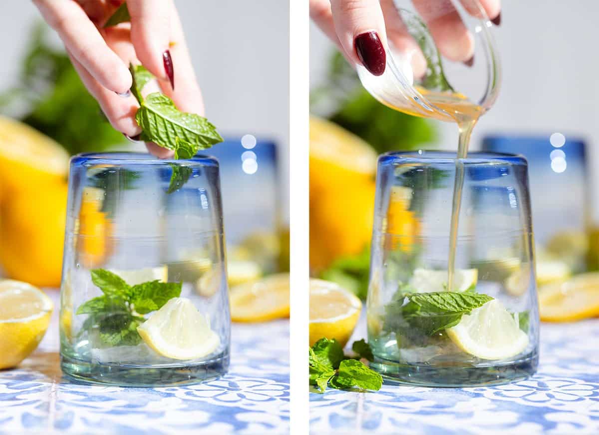 A hand adding fresh mint leaves into a short glass with a blue rim and pouring in lemon syrup.