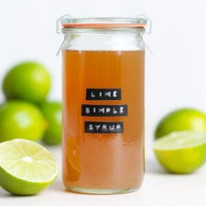 Dark yellow syrup in a glass jar with a black embossed label that says lime simple syrup.