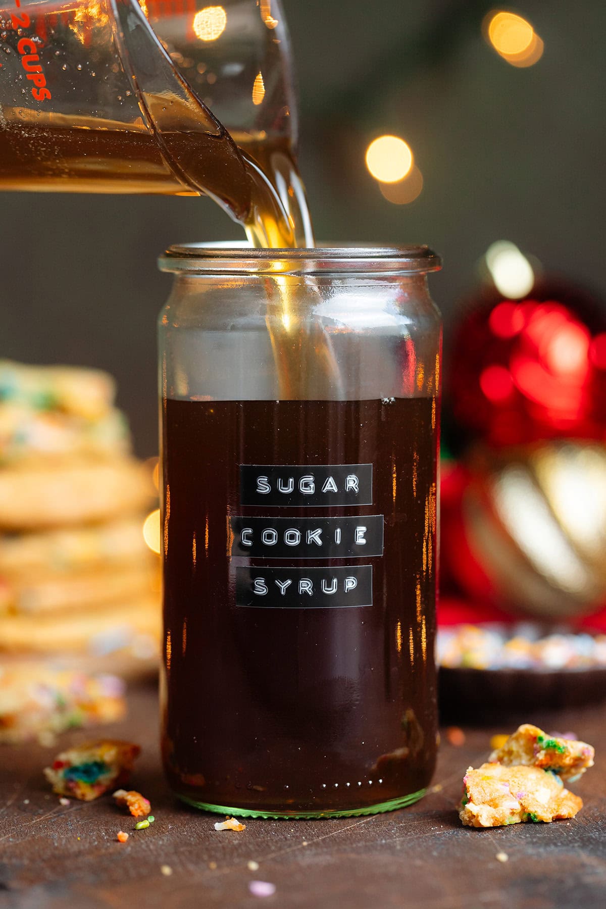 Dark amber simple syrup being poured into a glass jar.