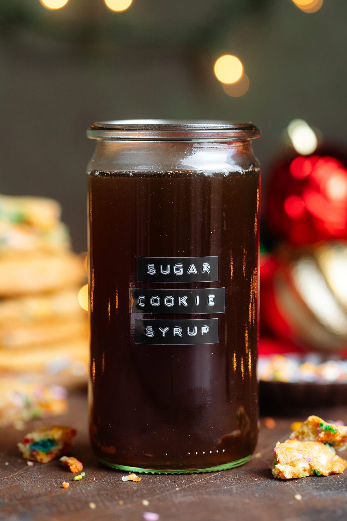 Dark brown syrup in a glass jar without a lid and an embossed label that says sugar cookie syrup.