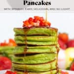 A stack of green pancakes topped with chopped strawberries being drizzled with maple syrup.