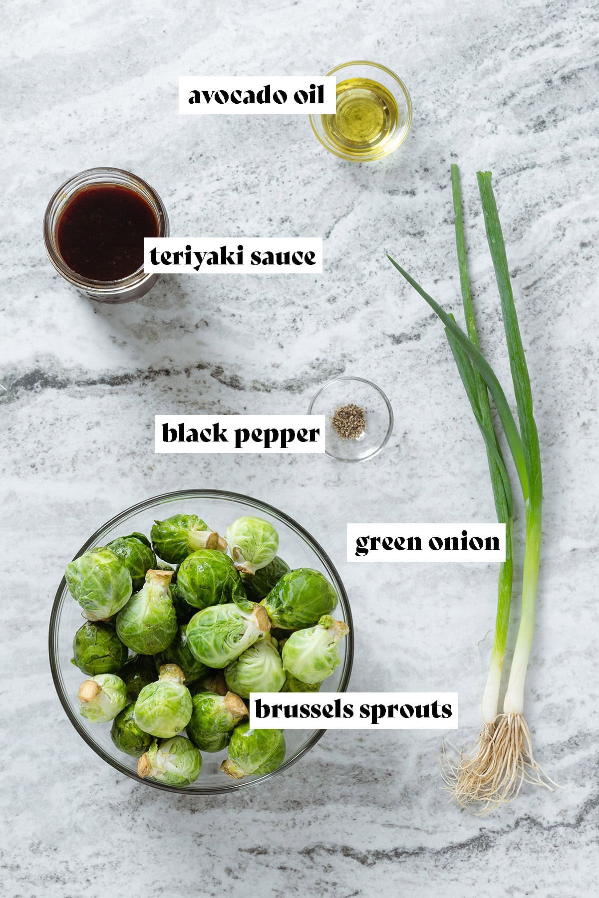 Ingredients like brussels sprouts, green onion, teriyaki sauce, and avocado oil in glass bowls.