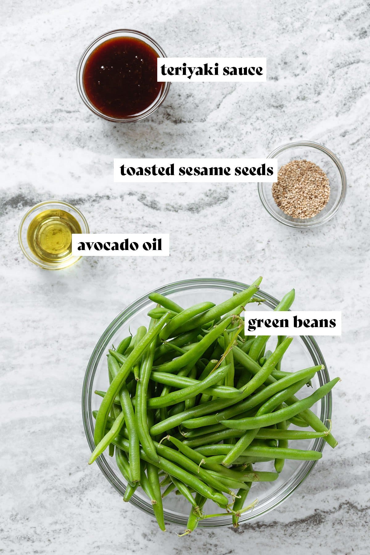 Green beans, teriyaki sauce, avocado oil, and sesame seeds in glass bowls.