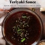 Dark teriyaki sauce in a glass bowl garnished with green onion and sesame seeds.