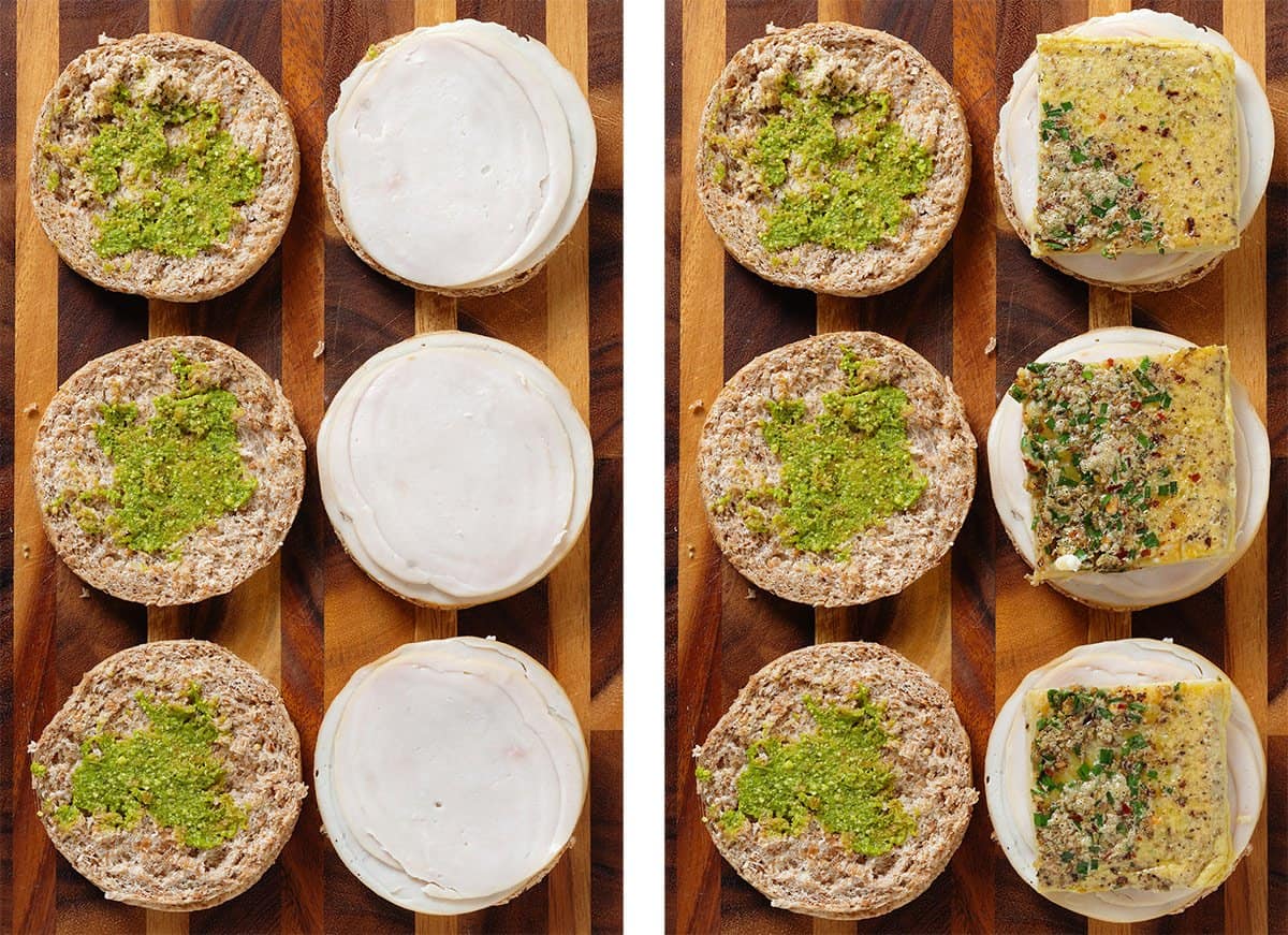 Three English muffins sliced in half topped with pesto, turkey ham, and a square of baked eggs.