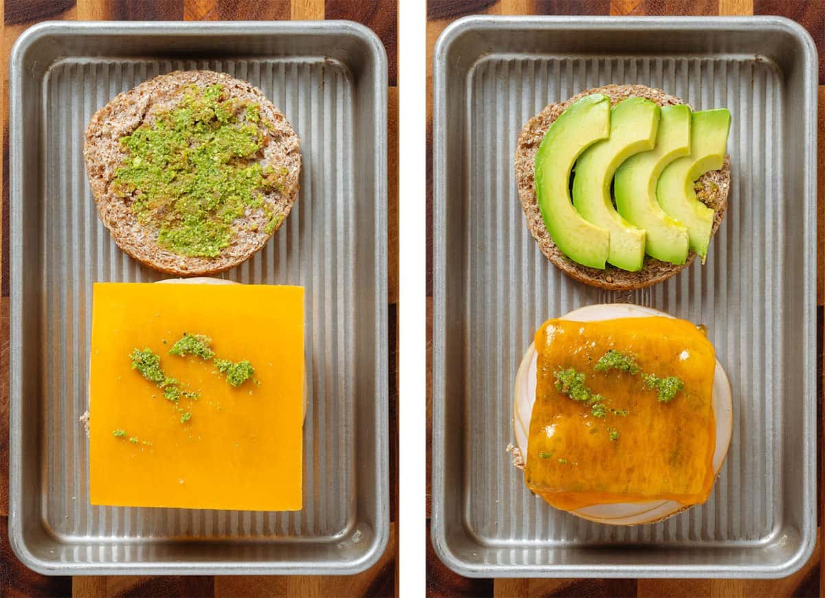 A breakfast sandwich with ham, cheddar cheese, egg, and pesto before and after toasting on a baking sheet with added avocado slices once toasted.
