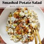 Crispy potato salad with yogurt mayo dressing garnished with bit of more crispy potatoes and fresh dill in a white bowl.