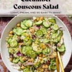 Cucumber and couscous salad in a large white bowl with gold utensils on a marble background.