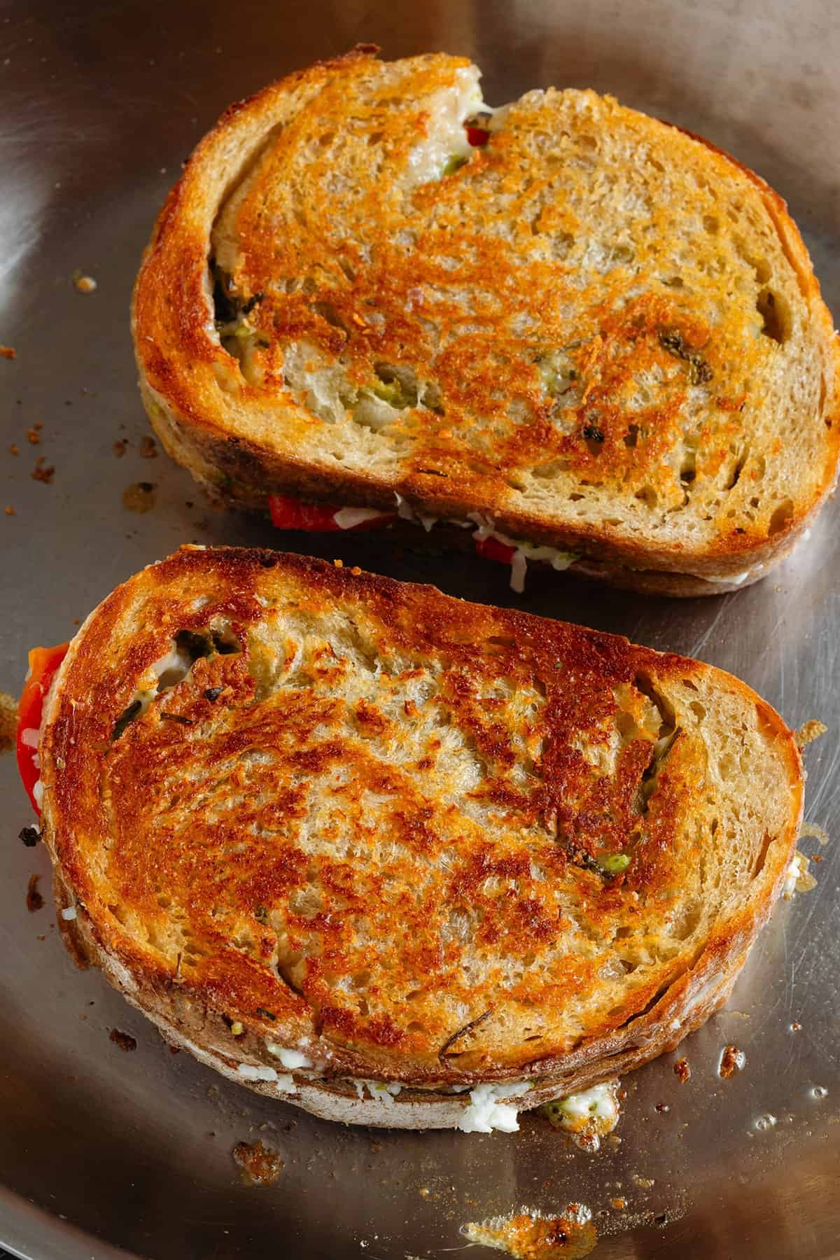 Grilled cheese cooking in a pan with butter showing how golden and crispy it gets.