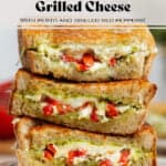 Three slices of grilled cheese with red peppers and pesto stacked on top of each other showing what's inside.