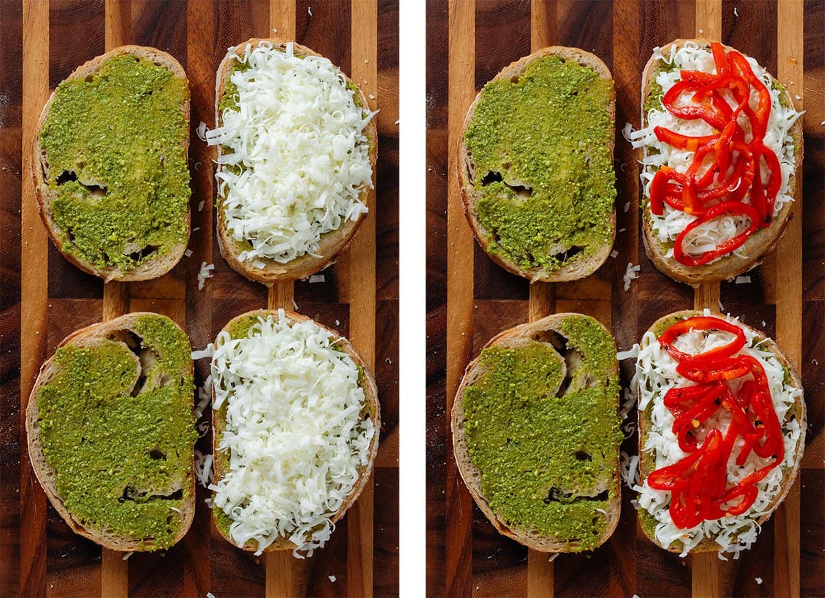 Slices of bread topped with pesto, grated cheese, and sliced roasted red peppers.