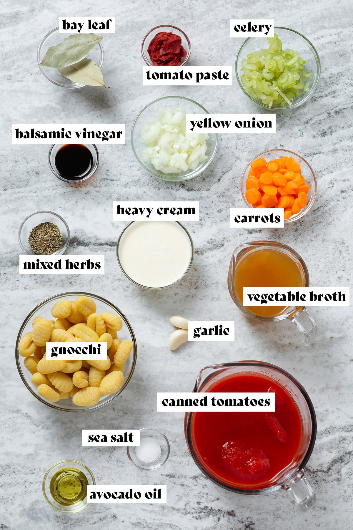 Ingredients like can canned tomatoes, gnocchi, vegetable broth, heavy cream, and veggies all laid out in small glass bowls.