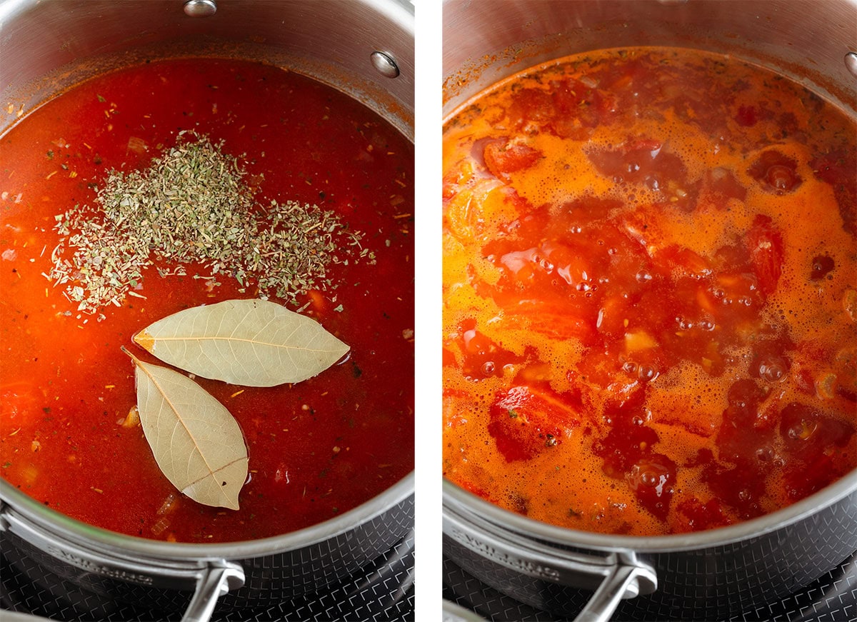 Tomato soup cooking with dried herbs and bay leaves in a large pot on the stove.