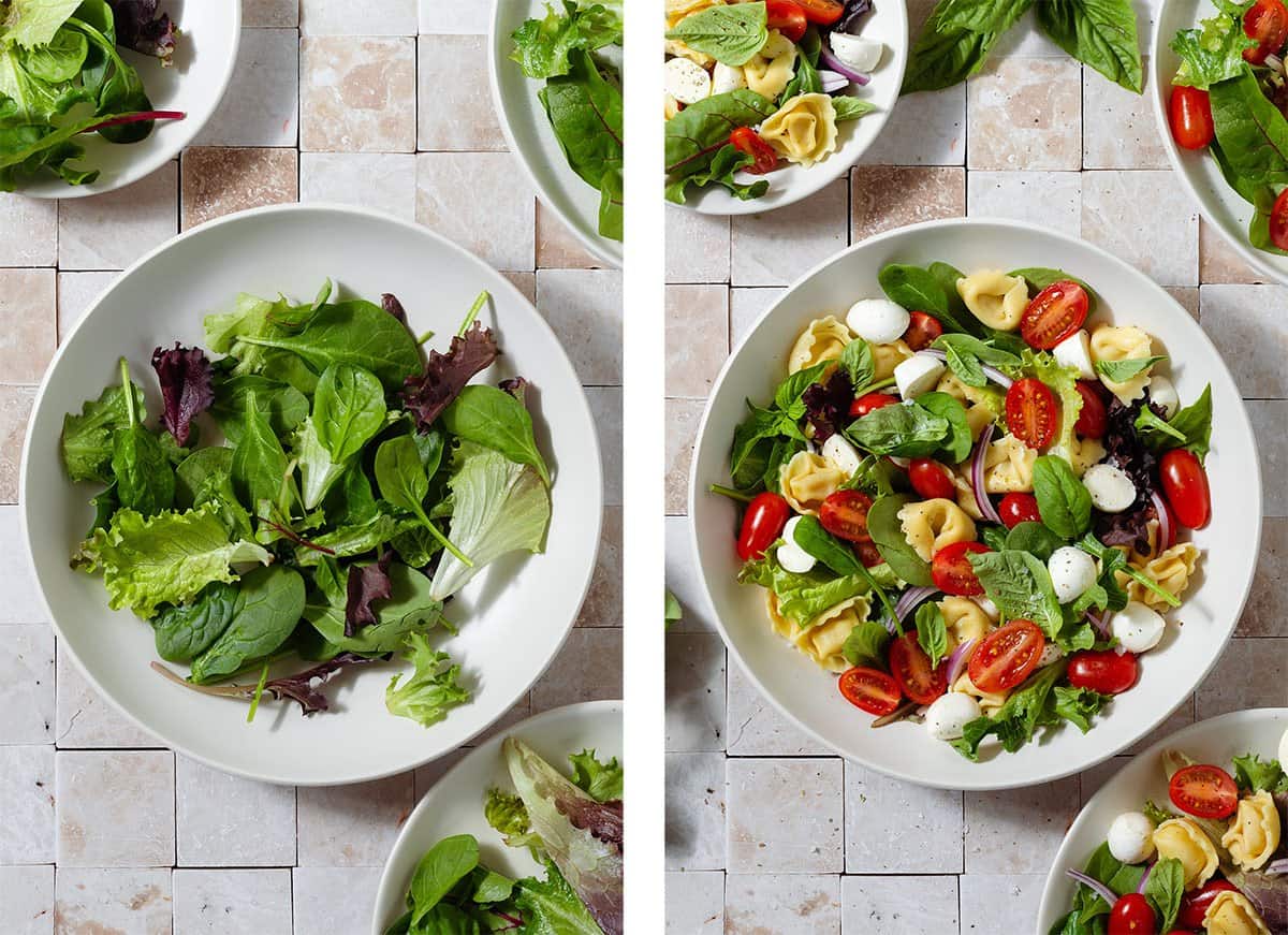 Tortellini Caprese Salad being layered in a large low bowl first with mixed greens, then the rest of the ingredients.