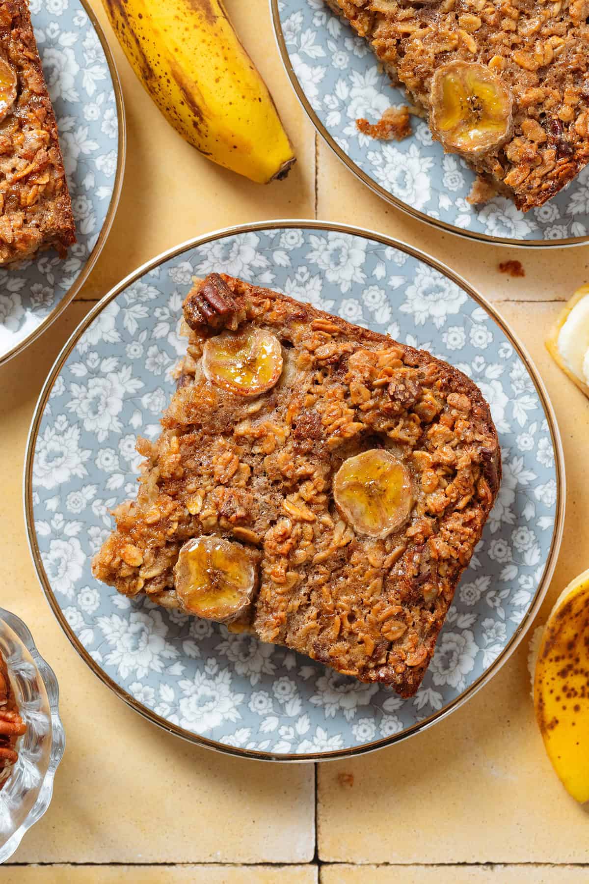 A slice of banana baked oatmeal with caramelized banana slices baked into it on top on a blue floral plate.