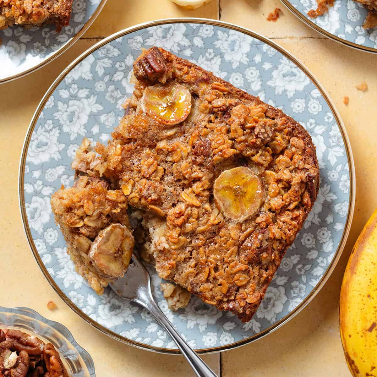A slice of banana baked oatmeal with caramelized banana slices baked into it on top on a blue floral plate.