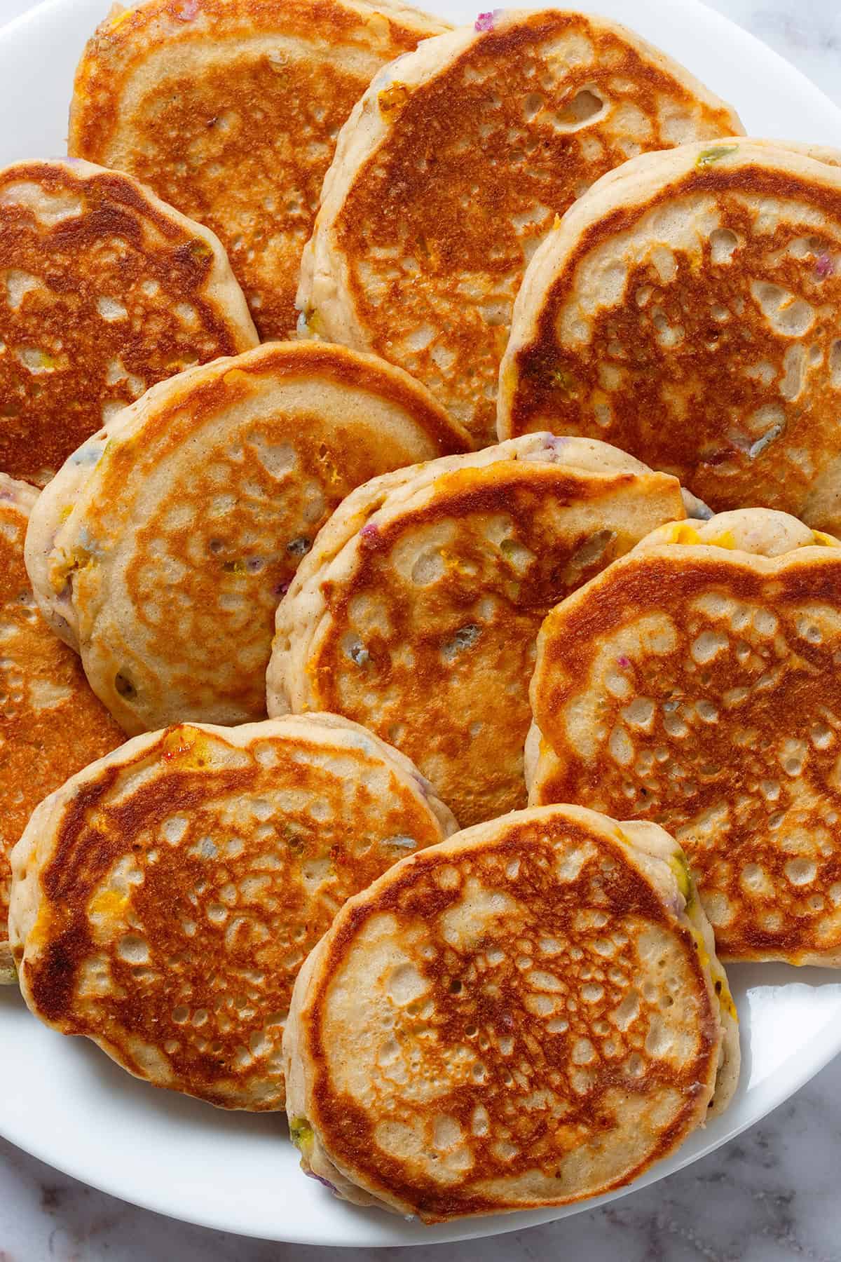 Golden vanilla pancakes with sprinkles inside laid out on a large white plate.
