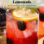 Dark red lemonade in a short glass garnished with blackberries, a lemon slice, and fresh thyme.