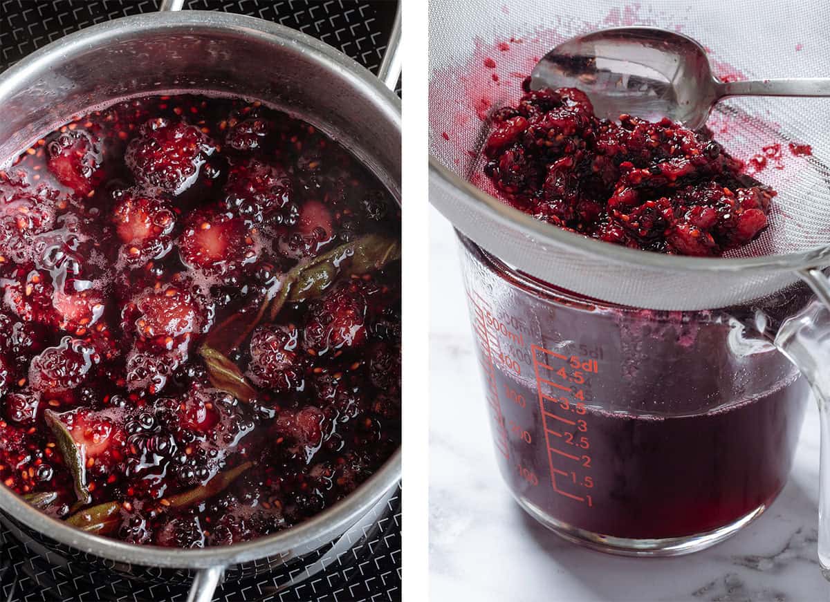 Blackberry syrup with fresh sage being strained through a fine mesh strainer into a large measuring cup.