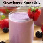 A light purple smoothie in a short glass garnished with a strawberry and blackberries around the glass.