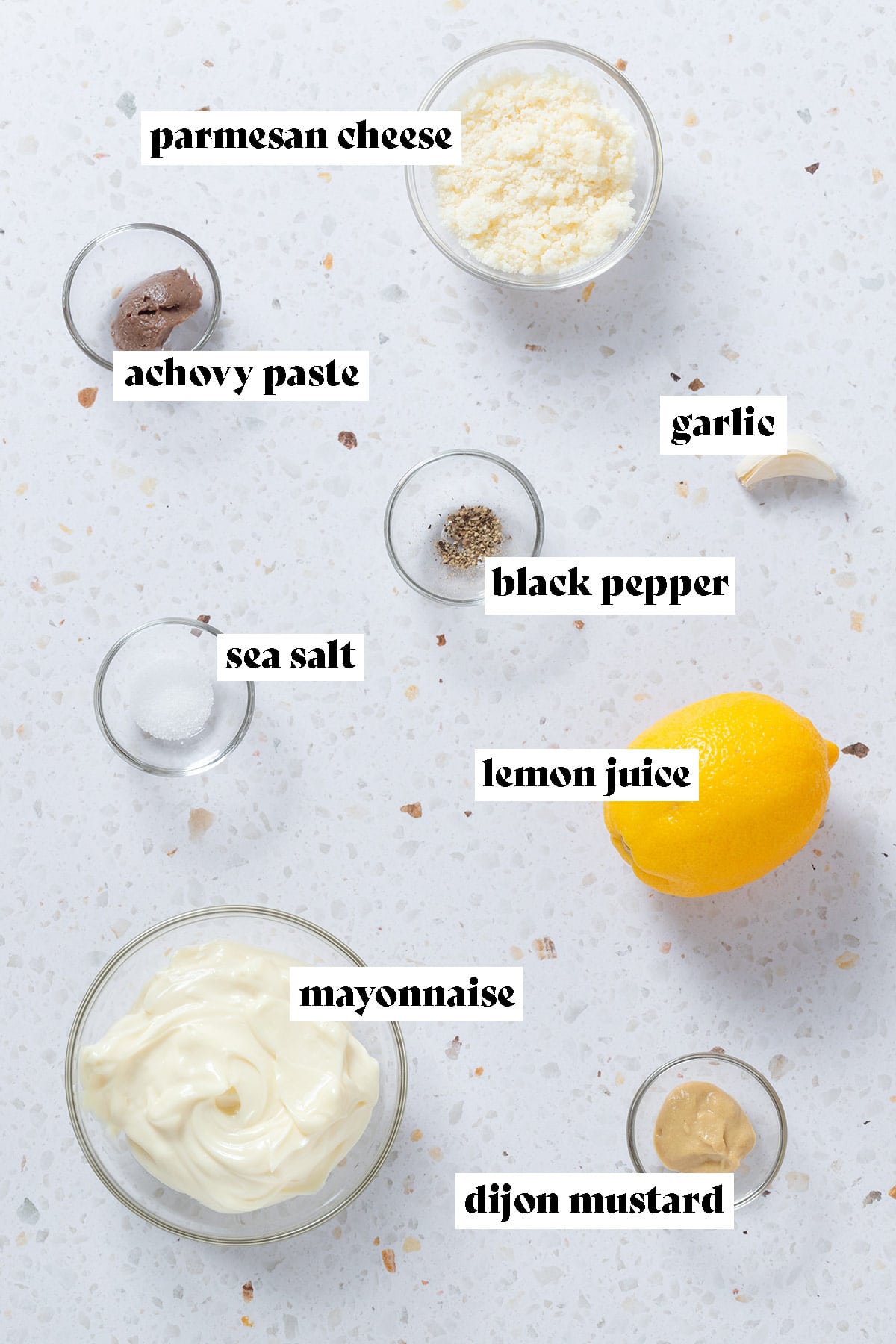 Ingredients like mayonnaise, parmesan cheese, salt, pepper, anchovy paste, and other ingredients in small glass bowls with text overlay.