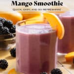 Vibrant purple smoothie in a short glass garnished with blackberries and slices of mango.