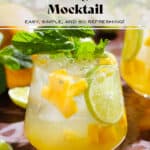 Bright yellow mango drink in a short glass garnished with fresh mint, a lime slice, and diced mango.