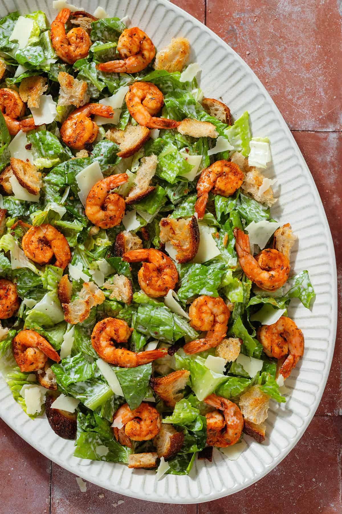 Caesar salad with spicy shrimp on a large oval serving platter.