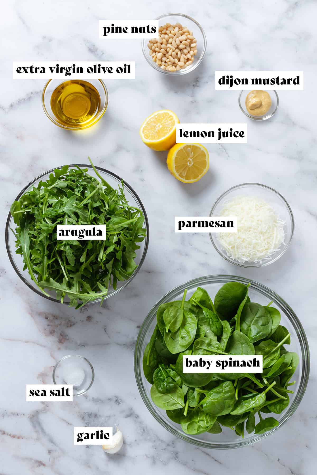 Bowls with baby spinach, arugula, pine nuts, parmesan, and other ingredients.