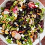 A bowl on blueberry salad with mixed greens, radishes, toasted almonds, and shallots.