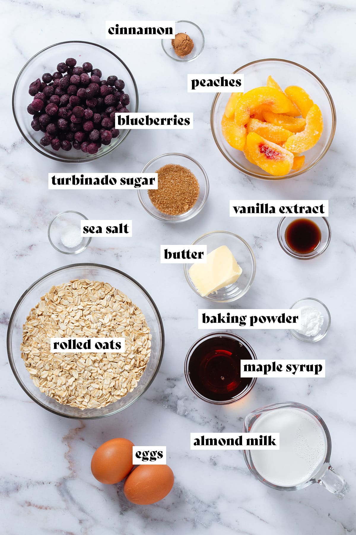 Ingredients like frozen blueberries, sliced peaches, oats, milk, butter, and maple syrup in small glass bowls with text overlay.