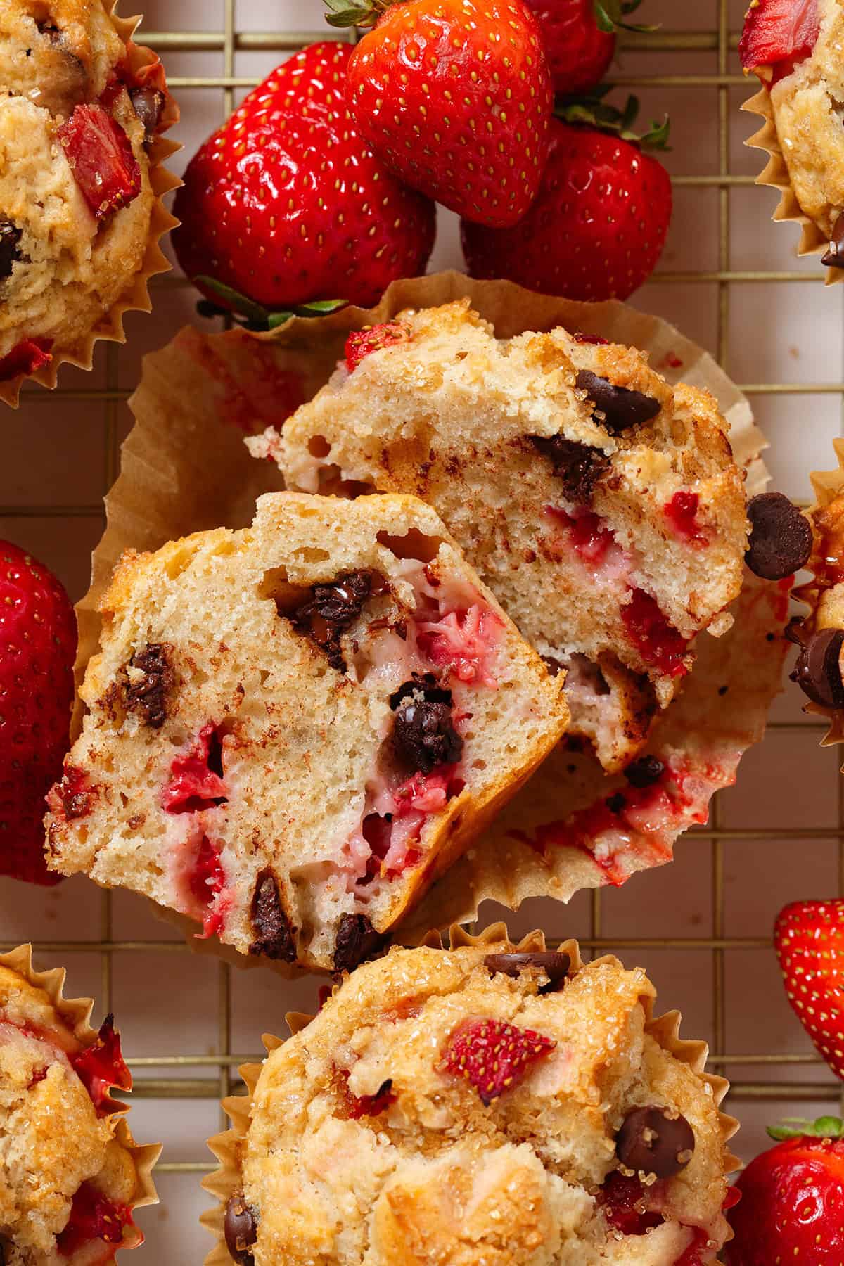 A muffin with strawberries and melted chocolate chips sliced on half to show the fluffy inside.