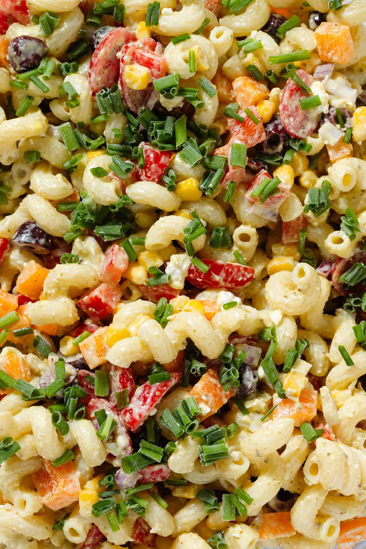 Creamy colorful veggie pasta salad sprinkled with chopped fresh chives.
