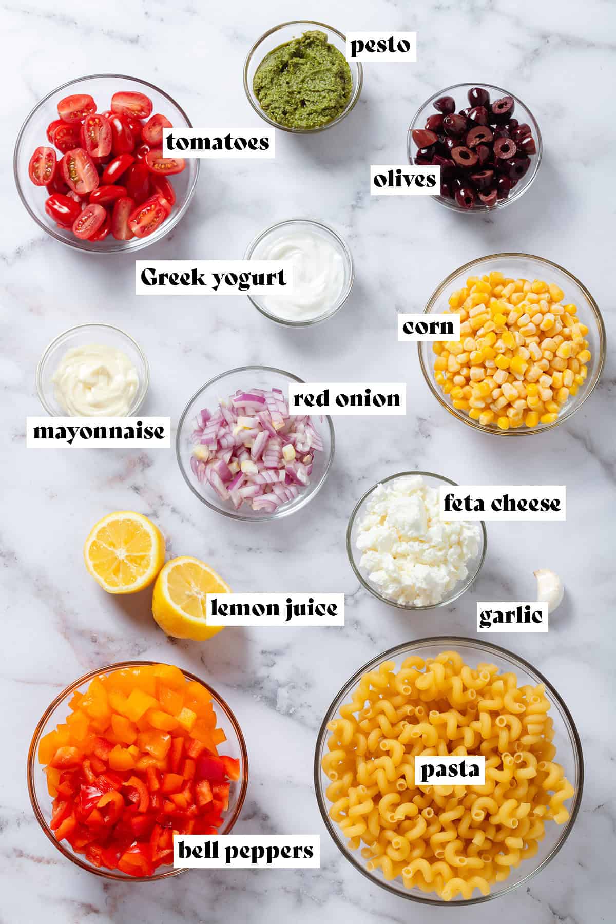 Small glass bowls with ingredients like pasta, corn, tomatoes, diced bell peppers, and olives.