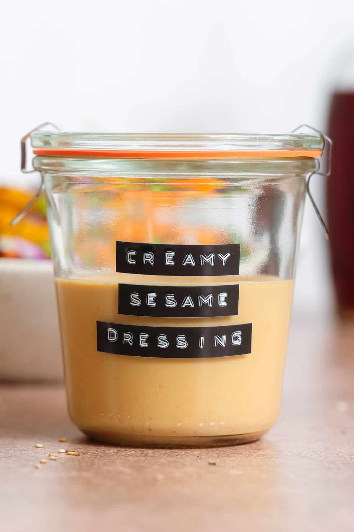 Golden creamy sesame dressing in a short glass jar.