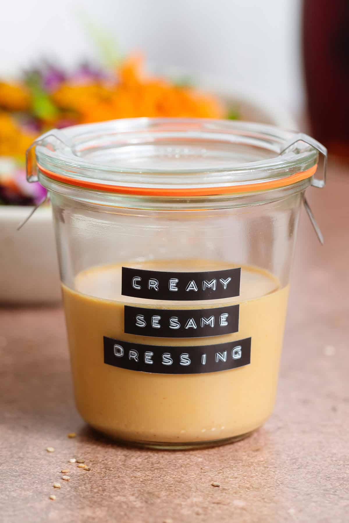 Golden creamy sesame dressing in a short glass jar.