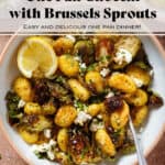 Crispy golden roasted brussels sprouts with gnocchi and feta in a white bowl with a beige rim garnished with lemon zest and two lemon wedges on the left.
