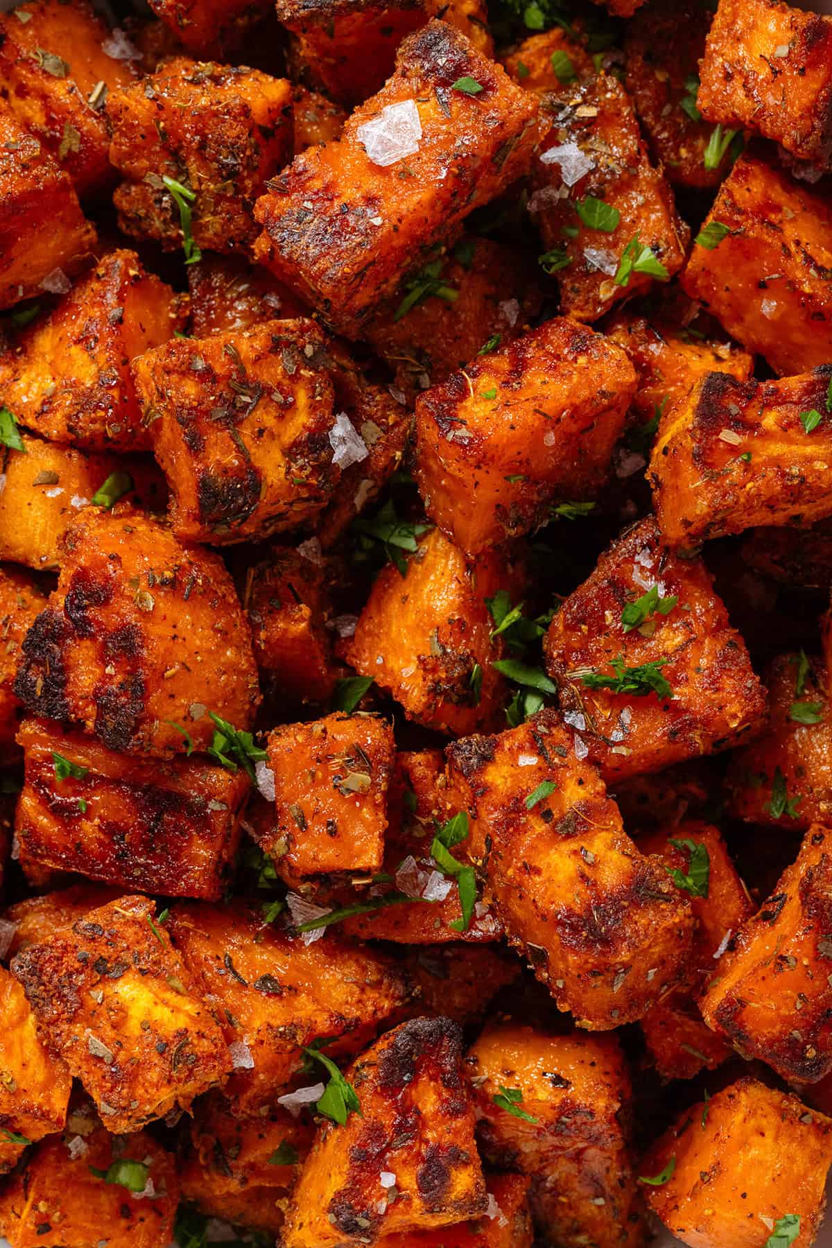 Crispy charred roasted diced sweet potatoes sprinkled with flaky sea salt and finely chopped fresh parsley.